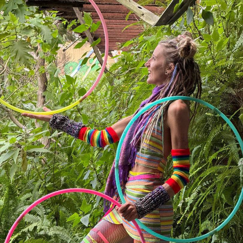 Smiling hooper holding colorful beginner hoops in a jungle garden