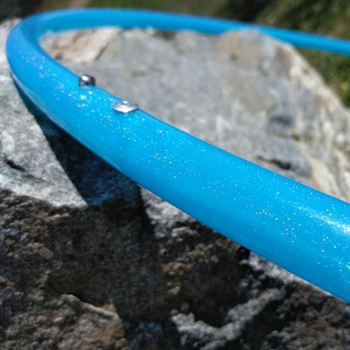 Blue glittery hoop on a rocky surface. The Spinsterz blue galactic glitter hula hoop.